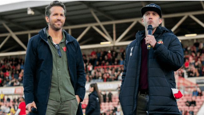 Ryan reynolds and rob McElhenney standing on Wrexham football club field for promo for 'Welcome to Wrexham' new documentary on Hulu