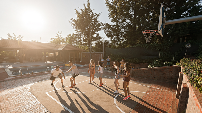 male and female youth kids playing basketball on outdoor court at park