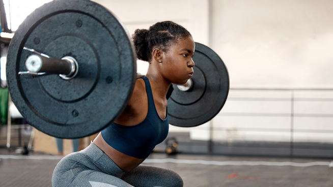 woman athlete performing squat with weights at the gym