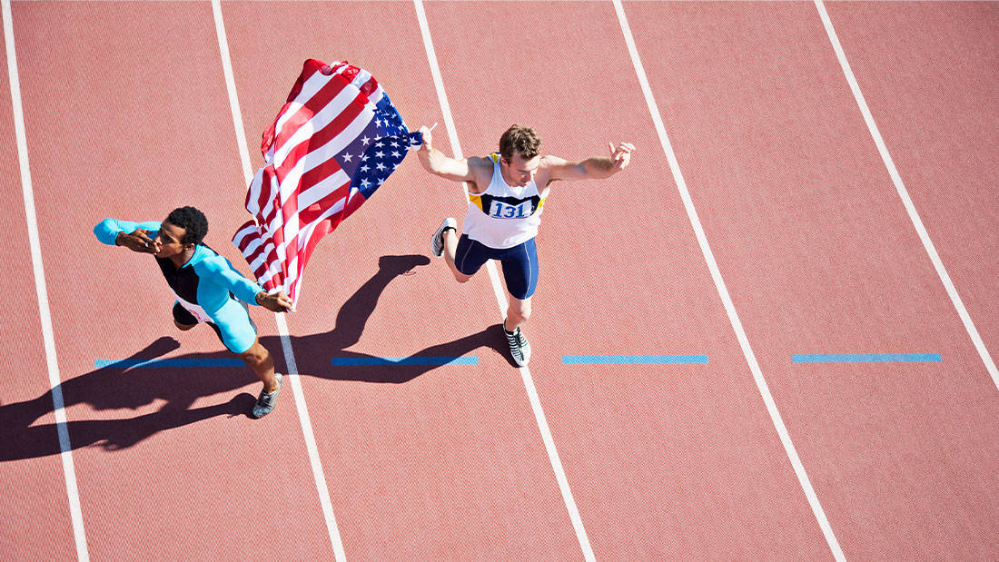 Male athlete carrying American flag on track at the Olympics