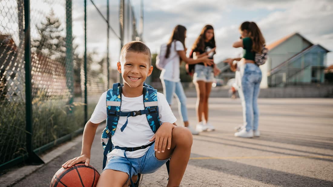 Young male with basketball outside at school